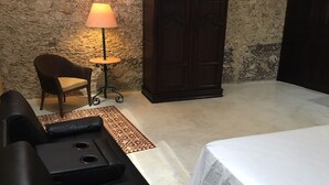 Un dormitorio con una cama, un sofá, una silla, una mesita con una lámpara y un armario.