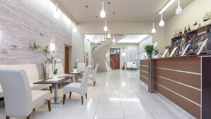 Eine moderne Hotelhalle mit Rezeption, Sitzgelegenheiten und einer Treppe.