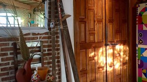 A room with a brick wall, wooden door, and a window with a floral curtain. - Ideal Para Familia Pequena O Grupo De Tres Amigos (Cuetzalan del Progreso)
