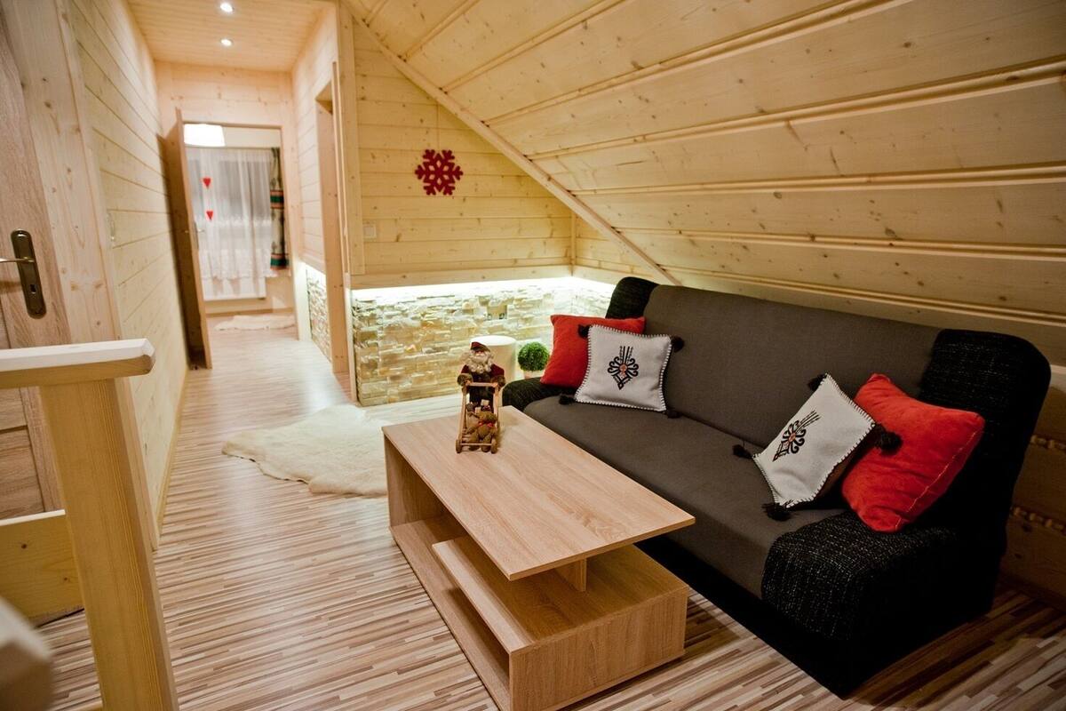 A cozy wooden interior with a sofa, pillows, and a small table.