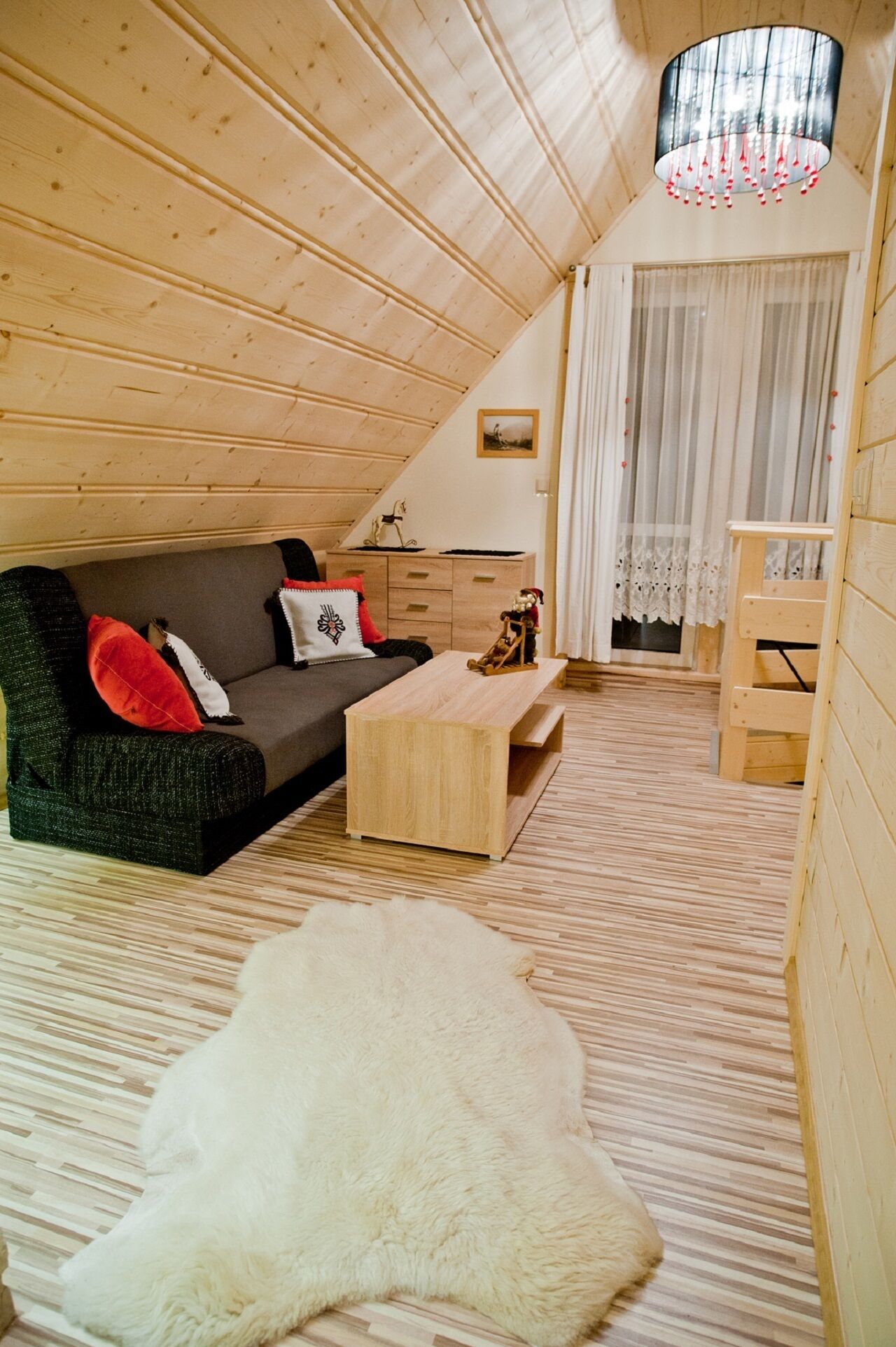 A cozy, wooden interior with a sofa, a small wooden table, and a white fur rug.