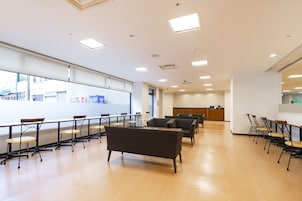 Una habitación amplia con una mesa grande y sillas, un sofá y un mostrador de recepción.
