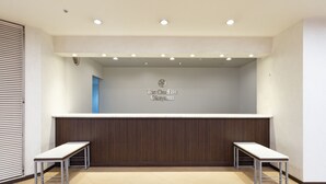 A reception desk with a sign reading "The OneFive Okayama" in a modern lobby with two benches and a wooden panel backdrop. - The OneFive Okayama (Okayama)