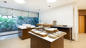 A reception area with a counter displaying baskets of towels and a large window with a stone wall view. - The OneFive Okayama (Okayama)