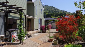 A residential area with a green house, a covered patio, and a garden with red flowers.