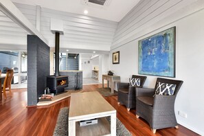 A modern living room with a fireplace, a dining area, and a kitchen in the background. - Ironbark Hill TJD Retreat (Pokolbin)