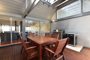 A modern kitchen with a large grill, wooden dining table, and chairs.