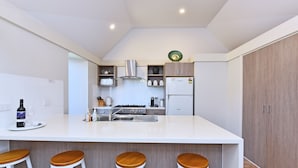 Et moderne køkken med en central ø, barstole, komfur og køleskab.
