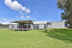 A modern mobile home with a covered patio area and a fenced yard.