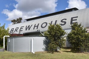 A building with the word 'BREWHOUSE' on its side, surrounded by trees and a clear sky.