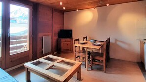 Un intérieur en bois comprenant une table à manger, des chaises, un téléviseur et une fenêtre.