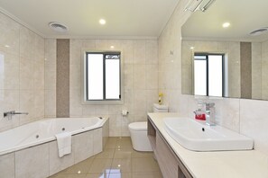 A modern bathroom with a bathtub, a toilet, and a sink.