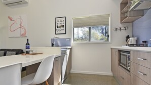 A modern kitchen with a white countertop, a sink, a window, and a dishwasher. - Ironbark Hill Spa Bath Villa 1- Tyrian (Pokolbin)