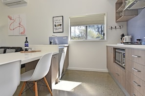 A modern kitchen with a white countertop, a sink, a window, and a dishwasher.