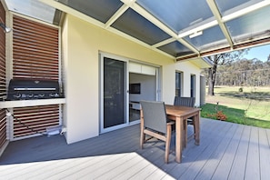 An outdoor patio with a grill, a table, and chairs.
