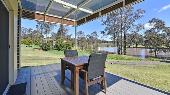 Una terraza con mesa y sillas que da a un lago y árboles.