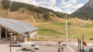 Un bâtiment avec un espace de stationnement, un fourgon et un paysage montagneux en arrière-plan.