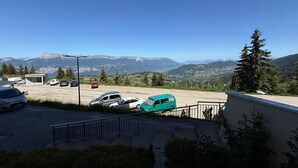 A parking area with vehicles, a building, and a mountainous landscape in the background. - 2-room rental for 5 people at the foot of the slopes (Les Adrets-Prapoutel)