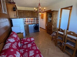 Uma cozinha compacta com armários de madeira, máquina de lavar roupa e área de jantar com mesa e cadeiras de madeira.