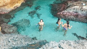 A natural pool with clear water, surrounded by rocky formations.