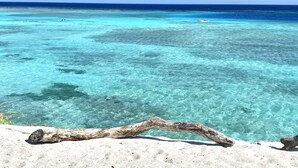 Klarer Blick auf einen Strand mit türkisblauem Wasser und sandigem Vordergrund.