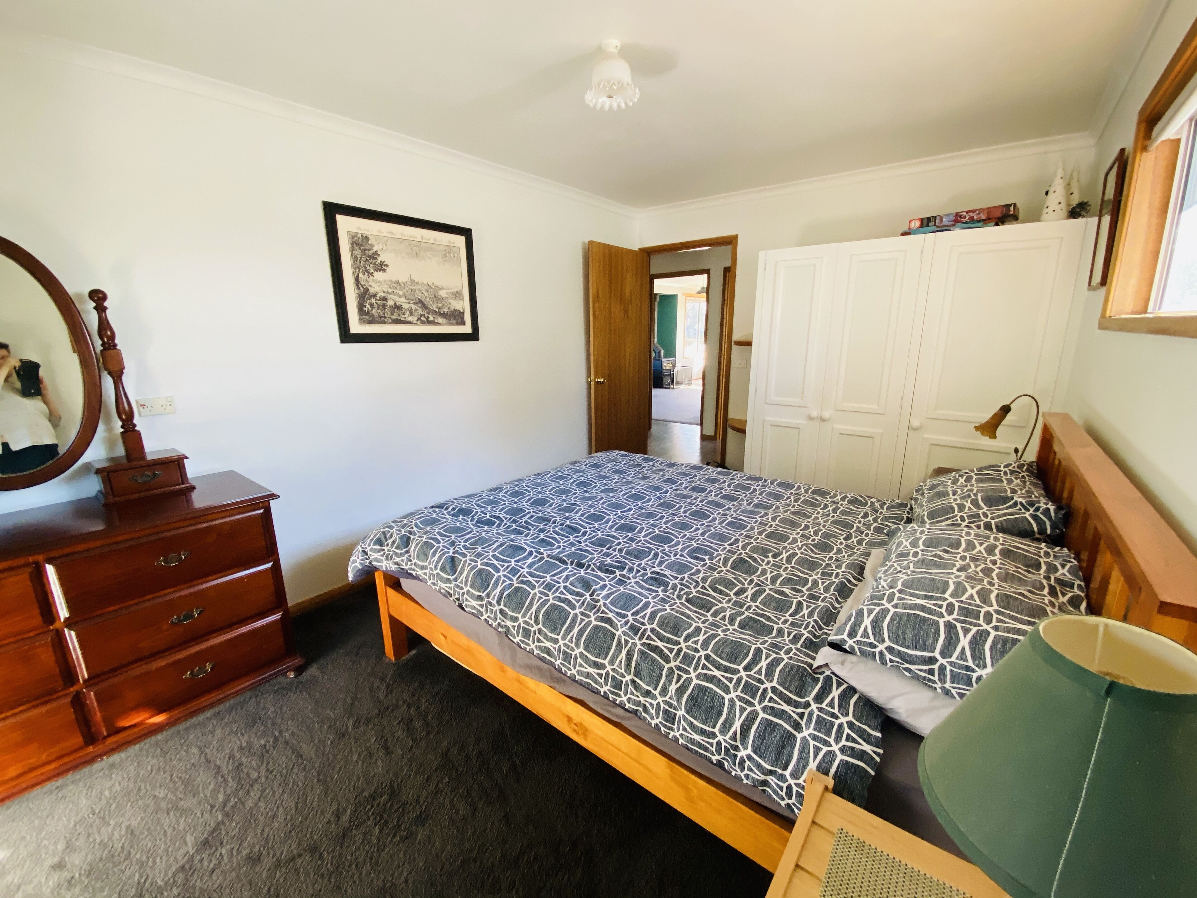 Un dormitorio con cama, cómoda, espejo y armario.
