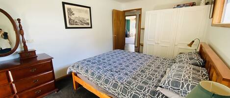 Un dormitorio con cama, cómoda, espejo y armario.