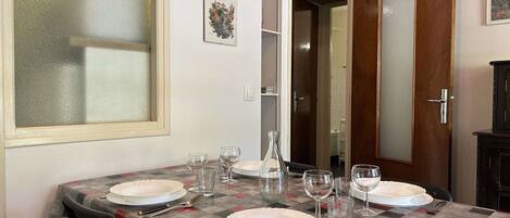 Un coin repas avec une nappe à carreaux, des assiettes blanches et des verres à vin.