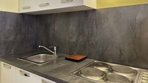 Een moderne keuken met een RVS spoelbak, een houten snijplank en een gasfornuis.