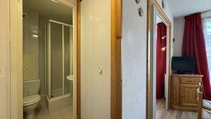 A bathroom with a toilet, shower, and a mirror.
