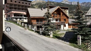 A mountain lodge with a wooden exterior, a balcony, and a view of the surrounding mountains.