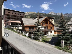 Un chalet de montagne avec une façade en bois, un balcon et une vue sur les montagnes environnantes.