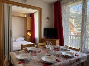 Une chambre avec un lit, une télévision et une table à manger dressée pour quatre personnes.