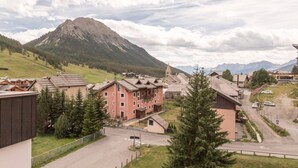 A mountain town with traditional buildings, a main road, and a prominent mountain in the background. - Cozy Ski Studio for 2 in Montgenèvre with Parking and Balcony (Montgenèvre)