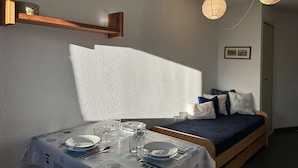 Una habitación acogedora con una mesa de comedor dispuesta para cuatro personas, un sofá con cojines y dos faroles de papel colgantes.