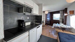 Una cocina compacta con microondas, cafetera y lavamanos.
