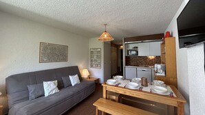 Un espacio habitable funcional con sofá, mesa de comedor y kitchenette.
