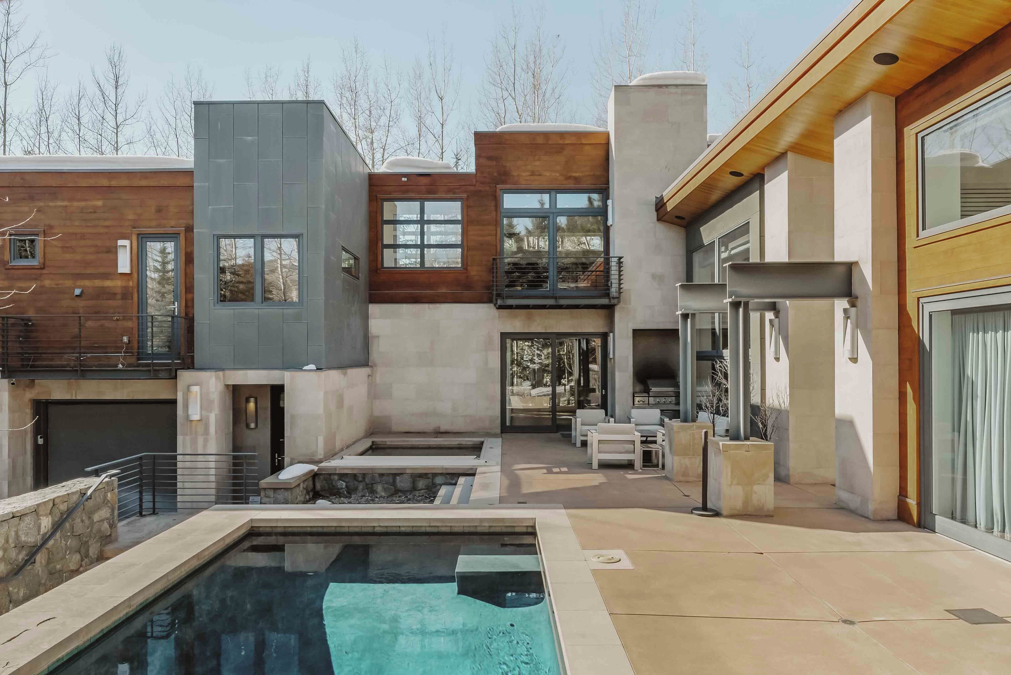 Une maison moderne dotée d’une piscine, d’un espace salon extérieur et d’un coin barbecue.