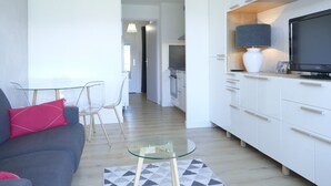 A modern living room with a sofa, glass coffee table, and a TV on a cabinet. - Renovated studio 4 pers with south balcony Les 2 Alpes (Les Deux Alpes)
