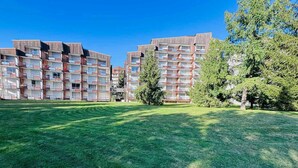 A multi-story residential building with balconies, surrounded by a well-maintained lawn and trees. - Renovated studio 4 pers with south balcony Les 2 Alpes (Les Deux Alpes)