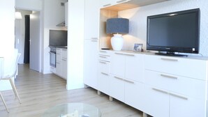 A modern kitchen with white cabinetry, a television, and a lamp. - Renovated studio 4 pers with south balcony Les 2 Alpes (Les Deux Alpes)