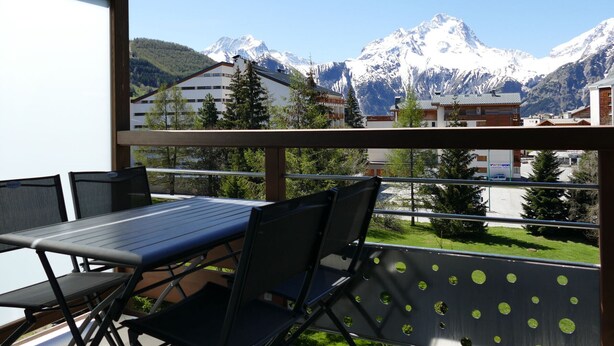 A balcony with a table and chairs, overlooking a mountain range. - Renovated studio 4 pers with south balcony Les 2 Alpes (Les Deux Alpes)
