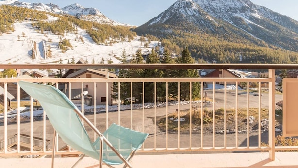 A balcony with a view of snow-covered mountains and a clear sky.