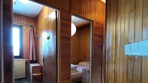 A wooden interior with a bed, a small table, and a chair.