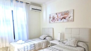 Ein Hotelzimmer mit zwei Betten, einem Deckenventilator, einer Klimaanlage und einem Bild an der Wand.