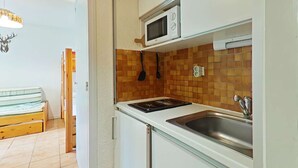 A compact kitchen with a microwave, a sink, and a tiled backsplash.