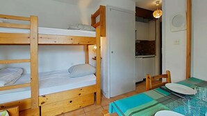 A bunk bed room with a kitchen area visible through an open door.
