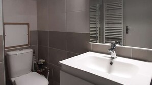 A bathroom with a toilet, sink, and mirror.