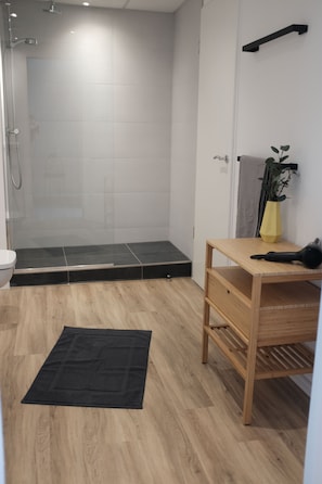 A modern bathroom with a shower, toilet, and wooden vanity.
