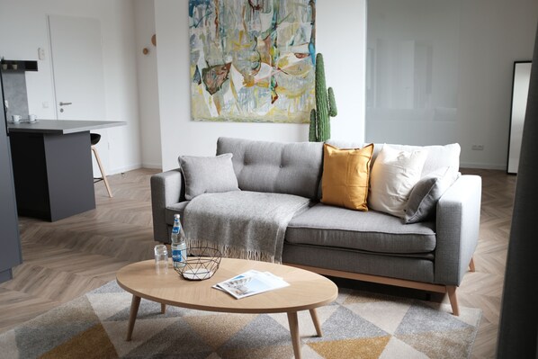 A modern living room with a grey sofa, a wooden coffee table, and a geometric patterned rug.